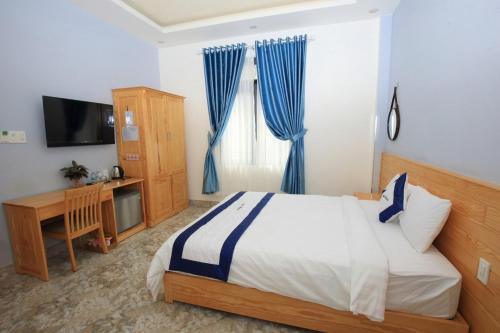 a bedroom with a bed and a television and blue curtains at Luan'S Villa in Da Lat