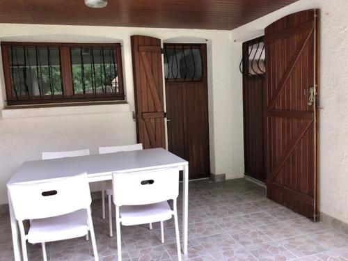 Cette chambre dispose d'une table, de chaises blanches et d'une porte. dans l'établissement Appartement donnant sur jardin avec terrasse., à La Roche-sur-Yon