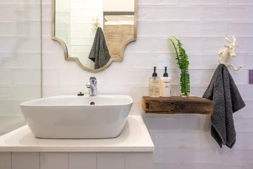 a bathroom with a white sink and a mirror at Driftwood by The Oyster Collection in Kenton on Sea