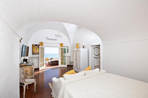 a white bedroom with a bed and a living room at La Casa di Peppe in Positano