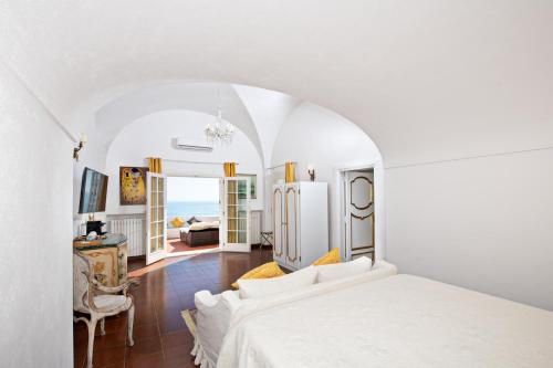 a white bedroom with a bed and a living room at La Casa di Peppe Guest House & Villa in Positano