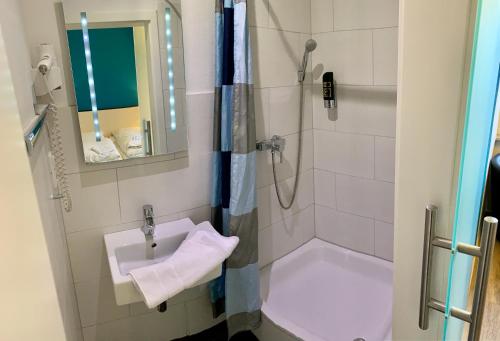 ein Bad mit einem Waschbecken und einer Dusche in der Unterkunft Gästehaus Seewarte in Flensburg