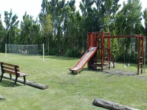 un parque con parque infantil con tobogán y banco en Cabañas La Chacra en El Calafate