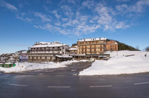 a snowy street in a town with snow covered buildings at Appartamenti al Prel in Prato Nevoso