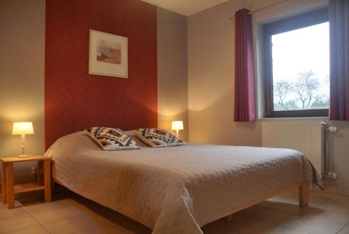 een slaapkamer met een bed met een rode muur bij Les Terriers Saint-Hubert in Hatrival