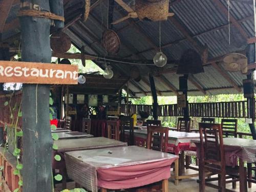 a restaurant with tables and chairs and a roof at Tree house Hostel Sigiriya in Sigiriya