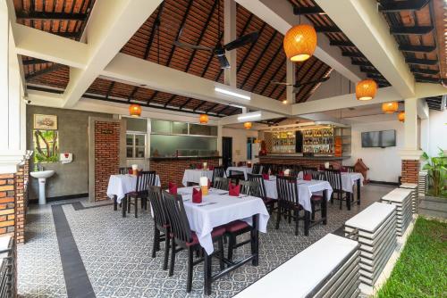 a restaurant with white tables and black chairs at Lavender Angkor Boutique in Siem Reap