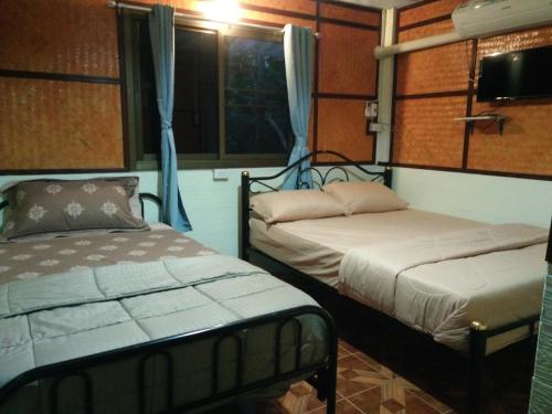 1 dormitorio con 2 camas y ventana en ต้งโฮมหละปูน ณ ตูบคำ en Lamphun