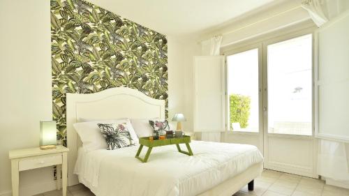a bedroom with a white bed with a large leafy wall at URBAN JUNGLE HOME (BORGO RIO FAVARA) in Ispica