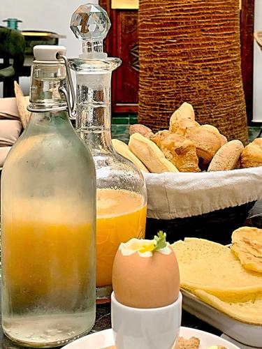 een tafel met een glazen fles sinaasappelsap en brood bij Riad Dar Yasaman in Marrakesh