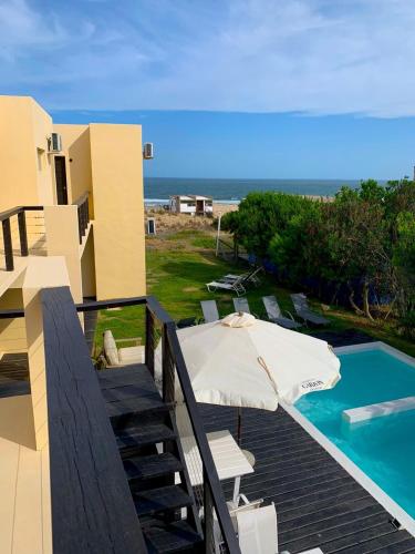 a balcony with an umbrella and a swimming pool at Terrazas de la Viuda in Punta Del Diablo