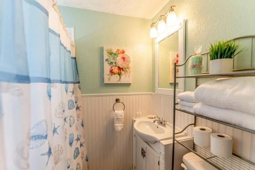 a bathroom with a sink and a shower curtain at CasaSeaSpell Galveston in Galveston