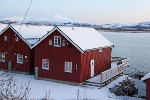 une maison rouge avec de la neige sur le toit dans l'établissement Rorbu Skreda, à Leknes