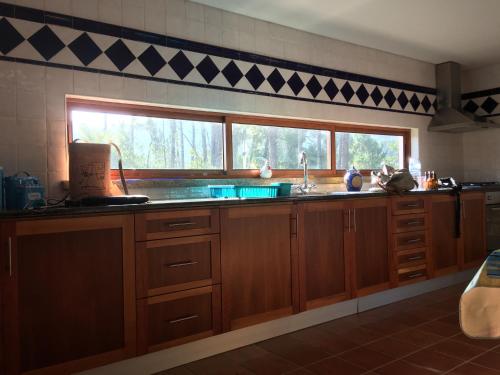 a kitchen with wooden cabinets and a large window at Casa Kika e Noelle in Castanheira de Pêra