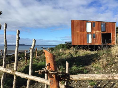 a house on top of a hill with a fence at El Coo Lodge in Queilén