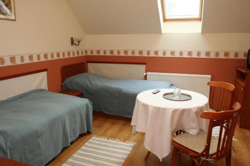 a room with two beds and a table and a window at Élet es Energia Egészségjavító Szalon in Nagykőrös