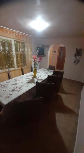 ein Esszimmer mit einem langen Tisch mit Stühlen und einer Vase mit Blumen in der Unterkunft Cabana Larisa in Cavnic