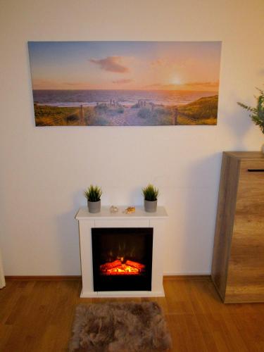 a living room with a fireplace with a painting on the wall at Ferienwohnung Seepferdchen in Timmendorfer Strand