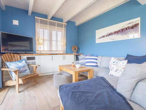 uma sala de estar azul com um sofá e uma televisão em Villa-Holzreich em Lohme