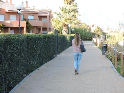 a woman is walking down a sidewalk at Urbanización Manilva Beach 21 in Manilva