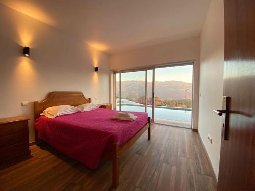 sypialnia z łóżkiem i dużym oknem w obiekcie Gondoriz-House w mieście Terras de Bouro