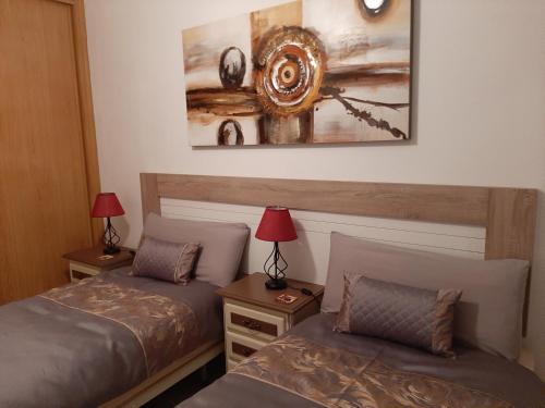 サン・ルイス・デ・サビニリャスにあるSunset Gem Aptのランプ2つと絵画が備わる客室内のベッド2台