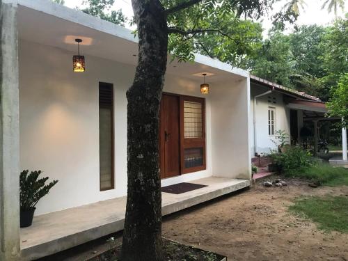a white house with a tree in front of it at The Loft in Midigama