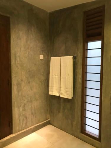 a bathroom with white towels hanging on a wall at The Loft in Midigama