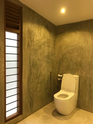 a bathroom with a white toilet in a room at The Loft in Midigama