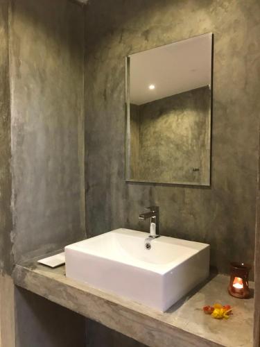 een badkamer met een witte wastafel en een spiegel bij The Loft in Midigama East