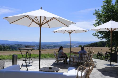two people sitting on a patio under umbrellas at Pension Geerlisburg in Kloten
