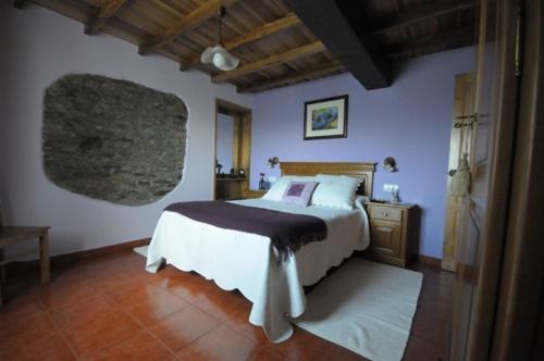 ein Schlafzimmer mit einem großen Bett und Holzboden in der Unterkunft Apartamentos Rurales Romallande in Puerto de Vega