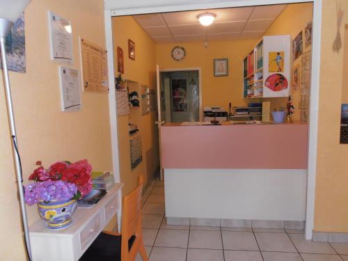a restaurant with a counter and flowers on a table at ALIOS Hôtel Restaurant in Bas-Mauco