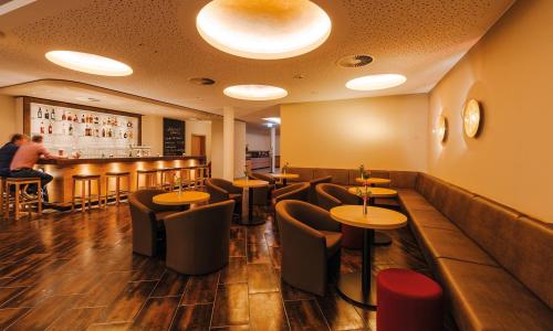 ein Restaurant mit Tischen und Stühlen und eine Bar in der Unterkunft Hotel Susato in Soest