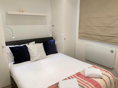 Cette petite chambre comprend un lit blanc avec des oreillers bleus. dans l'établissement The Notting Hill Gem, à Londres
