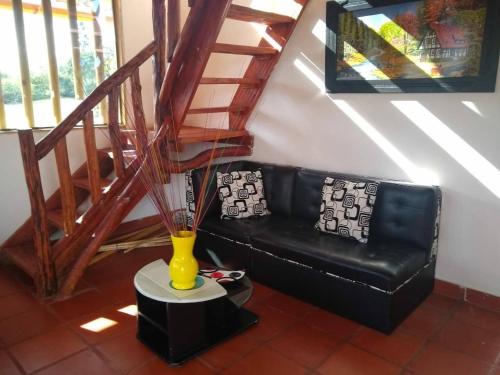 a black leather couch in a living room with a vase at CABAÑA LOS NOGALES in San Agustín