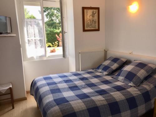 a bedroom with a bed with a blue and white checkered blanket at Gîte climatisé de La Haute Rue in Touvois