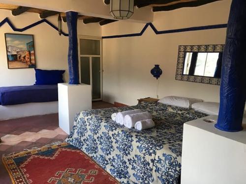 a bedroom with a bed with a blue and white blanket at Kasbah de Ouirgane in Ouirgane