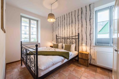 ein Schlafzimmer mit einem schwarzen Bett in einem Zimmer mit Fenstern in der Unterkunft Villa Monsei in Bad Schandau