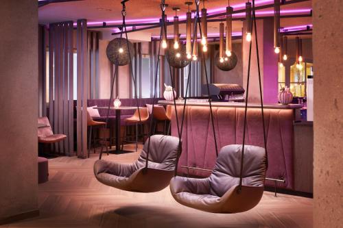 un restaurante con sillas y un bar con iluminación púrpura en Adler Inn Tyrol Mountain Resort SUPERIOR, en Tux