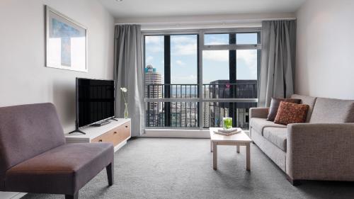 a living room with a couch and a television at Auckland Harbour Suites in Auckland