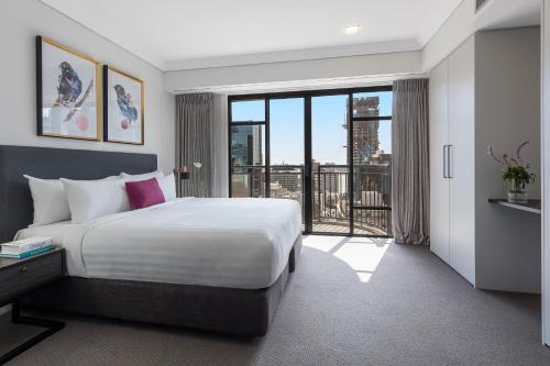 a hotel room with a bed, chair and a window at Avani Metropolis Auckland Residences in Auckland