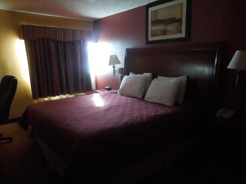 a hotel room with a bed with purple sheets and pillows at Ramada by Wyndham East Orange in East Orange