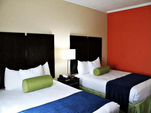 a hotel room with two beds and a red wall at Cityview Inn & Suites Downtown /RiverCenter Area in San Antonio