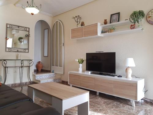 a living room with a couch and a tv at La Zenia Holiday Home in Playas de Orihuela