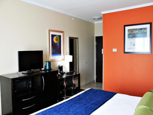 a bedroom with a bed with an orange accent wall at Cityview Inn & Suites Downtown /RiverCenter Area in San Antonio
