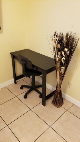 un bureau noir avec une chaise et un vase de fleurs dans l'établissement B Private Bedroom, à Orlando