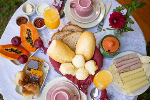 a plate of breakfast foods on a table at Chalés Recanto da cachoeira in Monte Verde