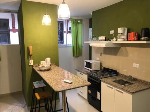eine Küche mit grünen Wänden und einer Theke mit einer Mikrowelle in der Unterkunft San Telmo Vivo in Buenos Aires