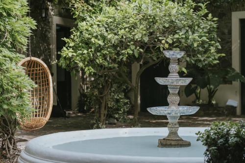 una fuente en un jardín con 2 sillas en Posada Plaza Mayor, en Colonia del Sacramento